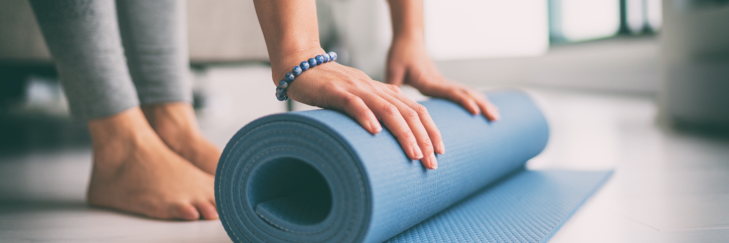 Eine Person rollt nach dem Kurs eine Yogamatte zusammen